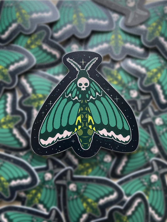 A sticker of a green and black death's head hawk moth with a skull design on its head.