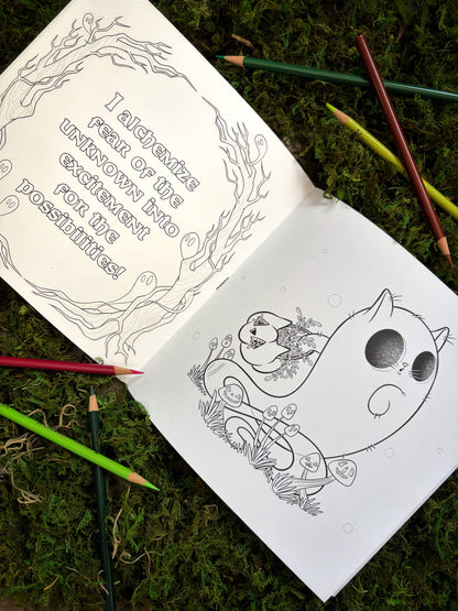 Coloring book with a cat ghost illustration and text on a mossy surface with colored pencils.